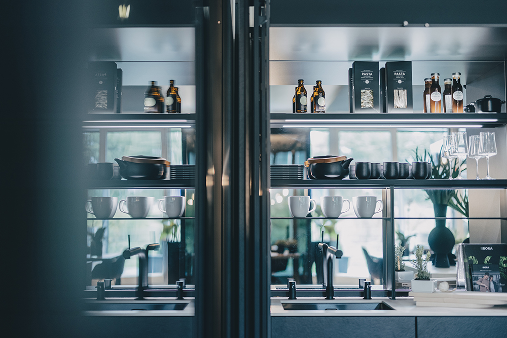 Beleuchtete vitrine mit geschirr hinter glas in der next125 küche